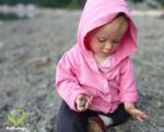 How babies learn: baby in a pink hoodie playing with rocks on the beach