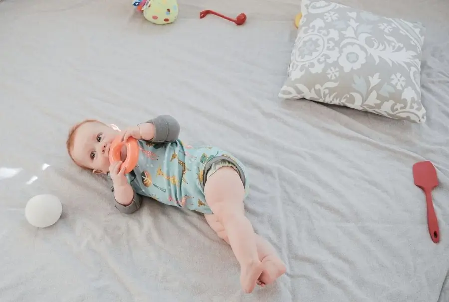 Baby engaging in one of the best baby activities: free play on the floor with simple toys and safe household objects