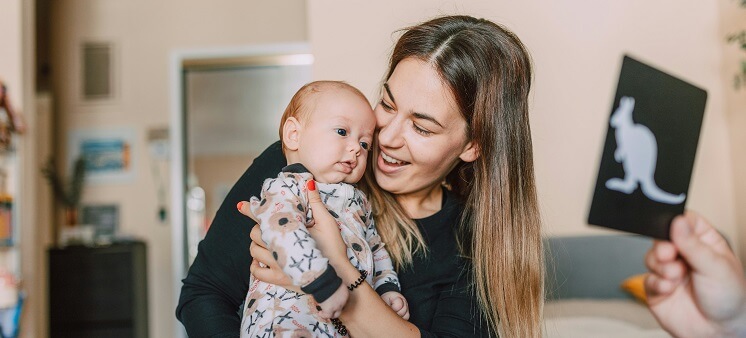 Mom holding baby looking at black-and-white flash cards for babies