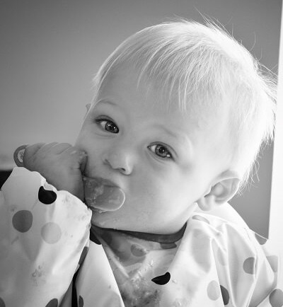 Baby wearing bib eating from spoon