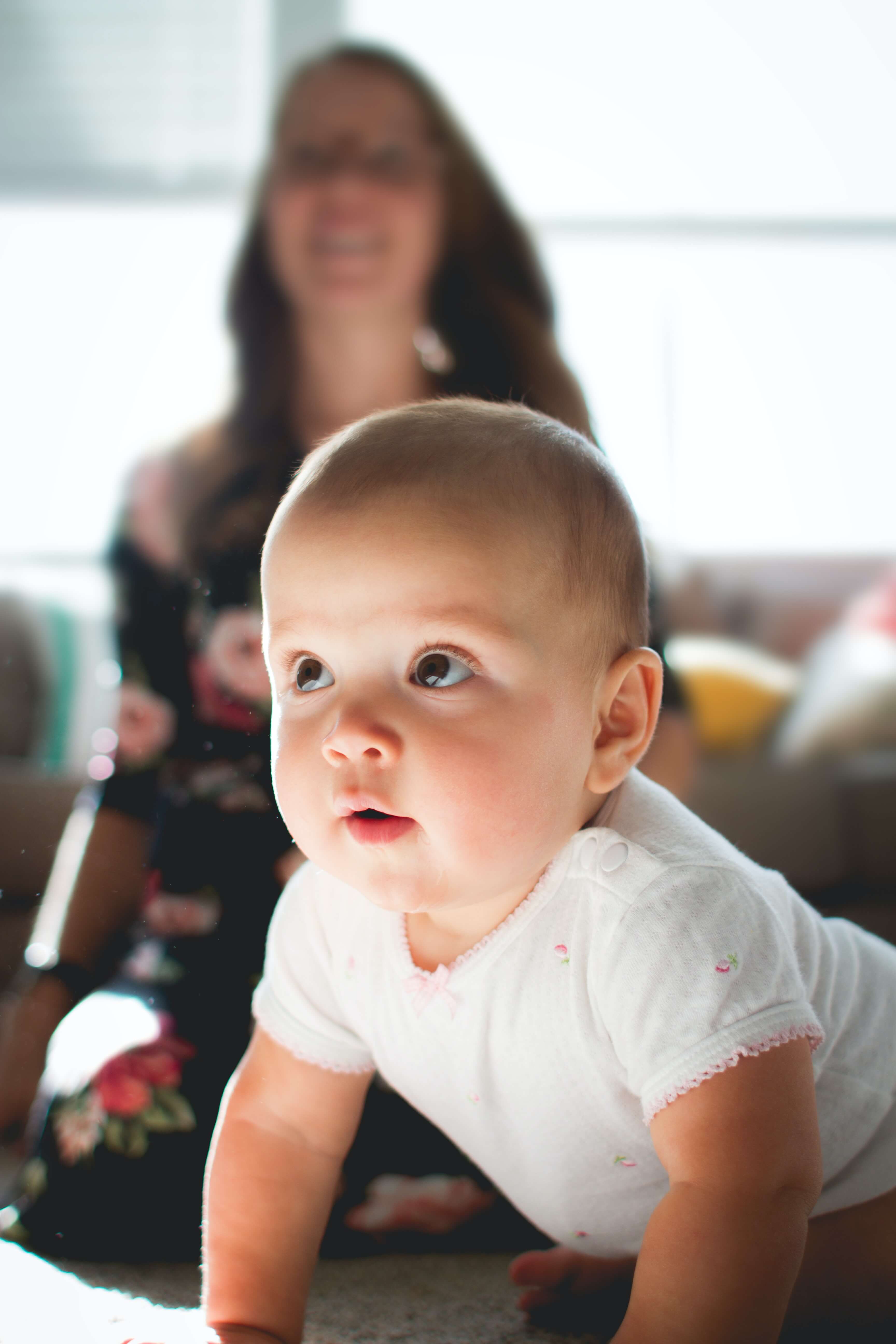 Baby looking away with mother sitting behind Baby looking away with mother sitting behind