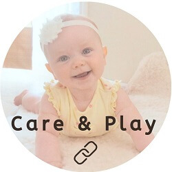 Smiling baby playing on her tummy in yellow romper and flower headband